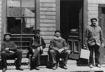 Quatres hommes se reposent en avant d'un magasin de Meteghan